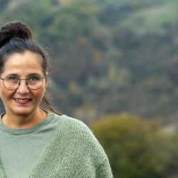 Businesscoachin Isa Hiemann lächelt vor einer grünen Hügellandschaft