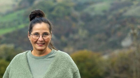 Businesscoachin Isa Hiemann lächelt vor einer grünen Hügellandschaft
